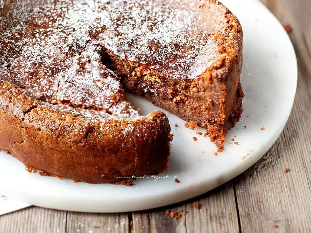 Torta soffice e golosa, uno dei tanti dolci con cioccolato al latte, spolverata di zucchero a velo su un piatto di marmo.