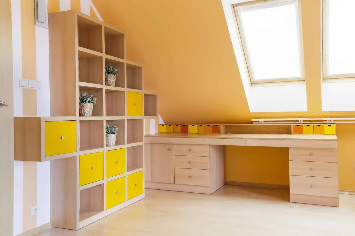 Colori vivaci per le pareti di una mansarda: arancione acceso e tocchi di giallo su una libreria modulare.