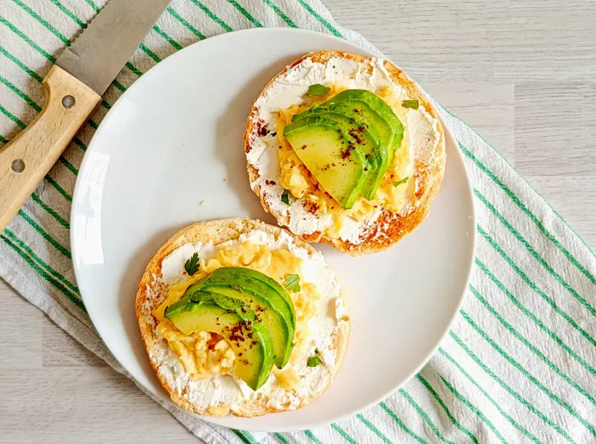 Deux toasts avec fromage frais, œufs brouillés et avocat. Un petit-déjeuner sain et savoureux, idéal pour maîtriser les calories.