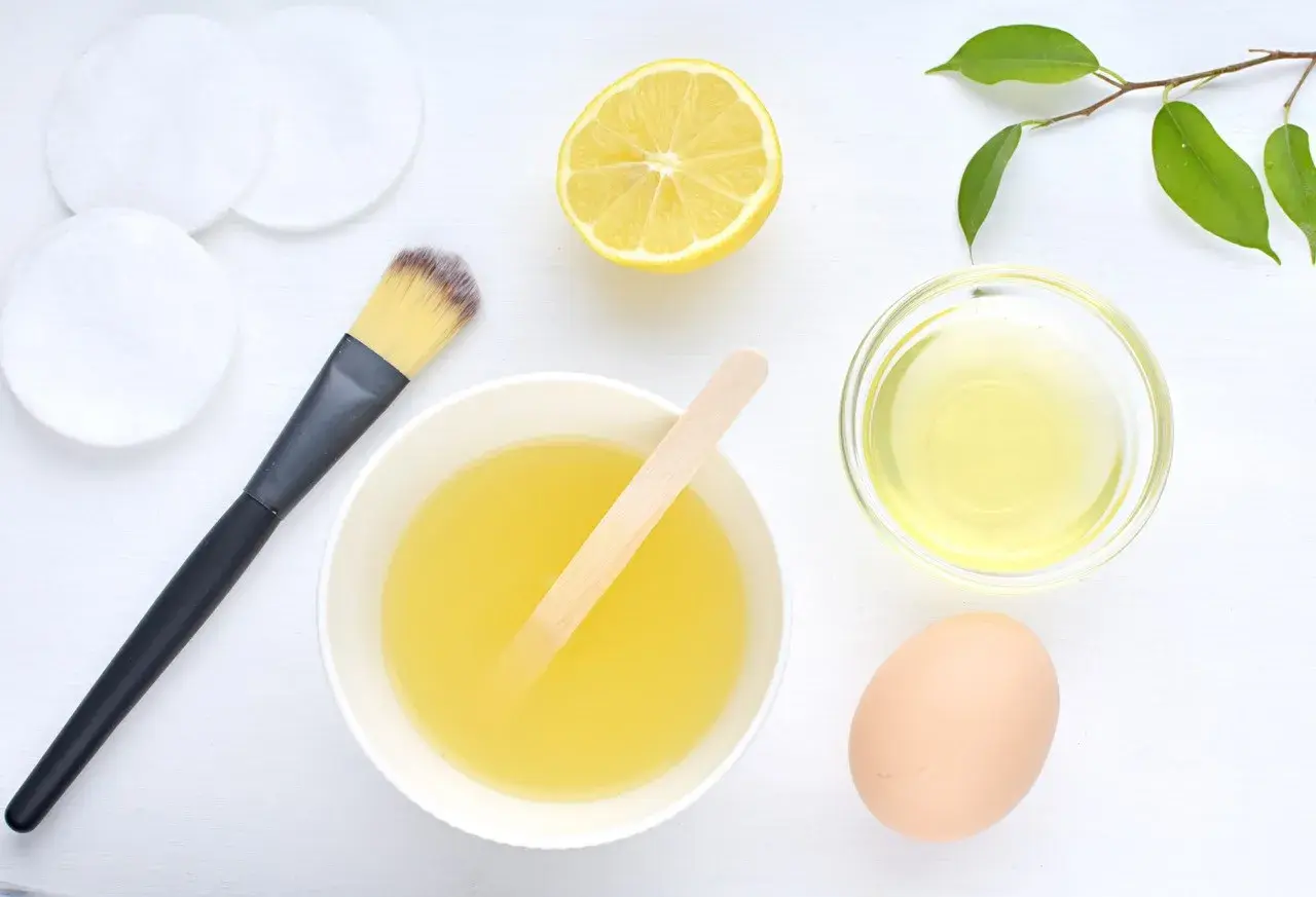 Ingredientes para una mascarilla de huevo para el pelo: huevo, limón, aceite y brocha.