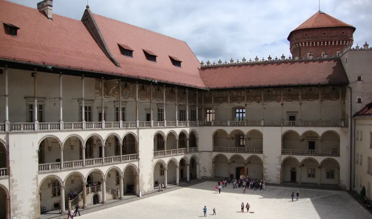 Dziedziniec zamku królewskiego na Wawelu, z arkadowymi krużgankami i wieżą. Ciekawostki o historii tego miejsca czekają na odkrycie.