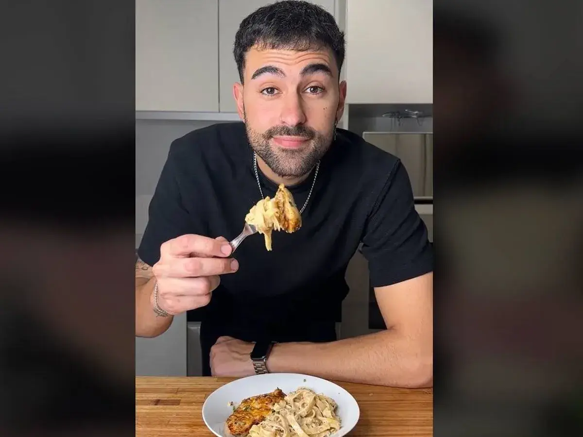 Hombre sonriendo mientras prueba unos deliciosos macarrones con pollo.