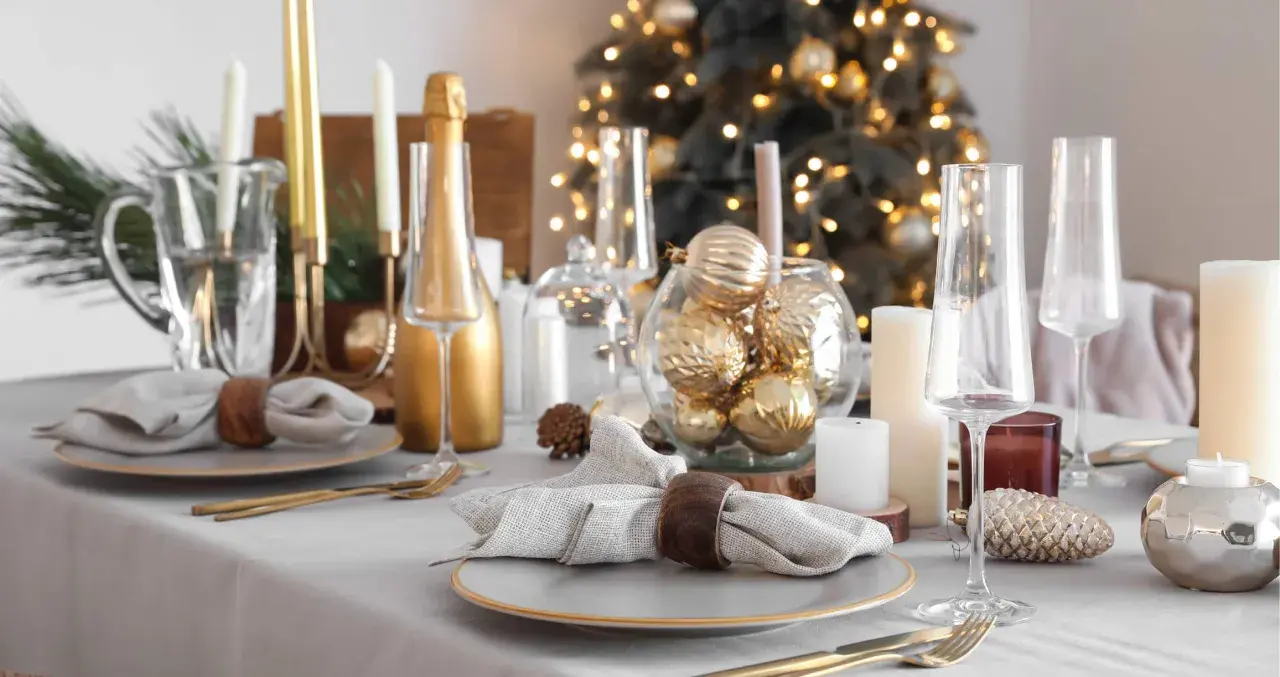 Festlich gedeckter Tisch Weihnachten mit goldenen Kugeln, Kerzen und Champagner. Ein eleganter Blickfang für die Feiertage.