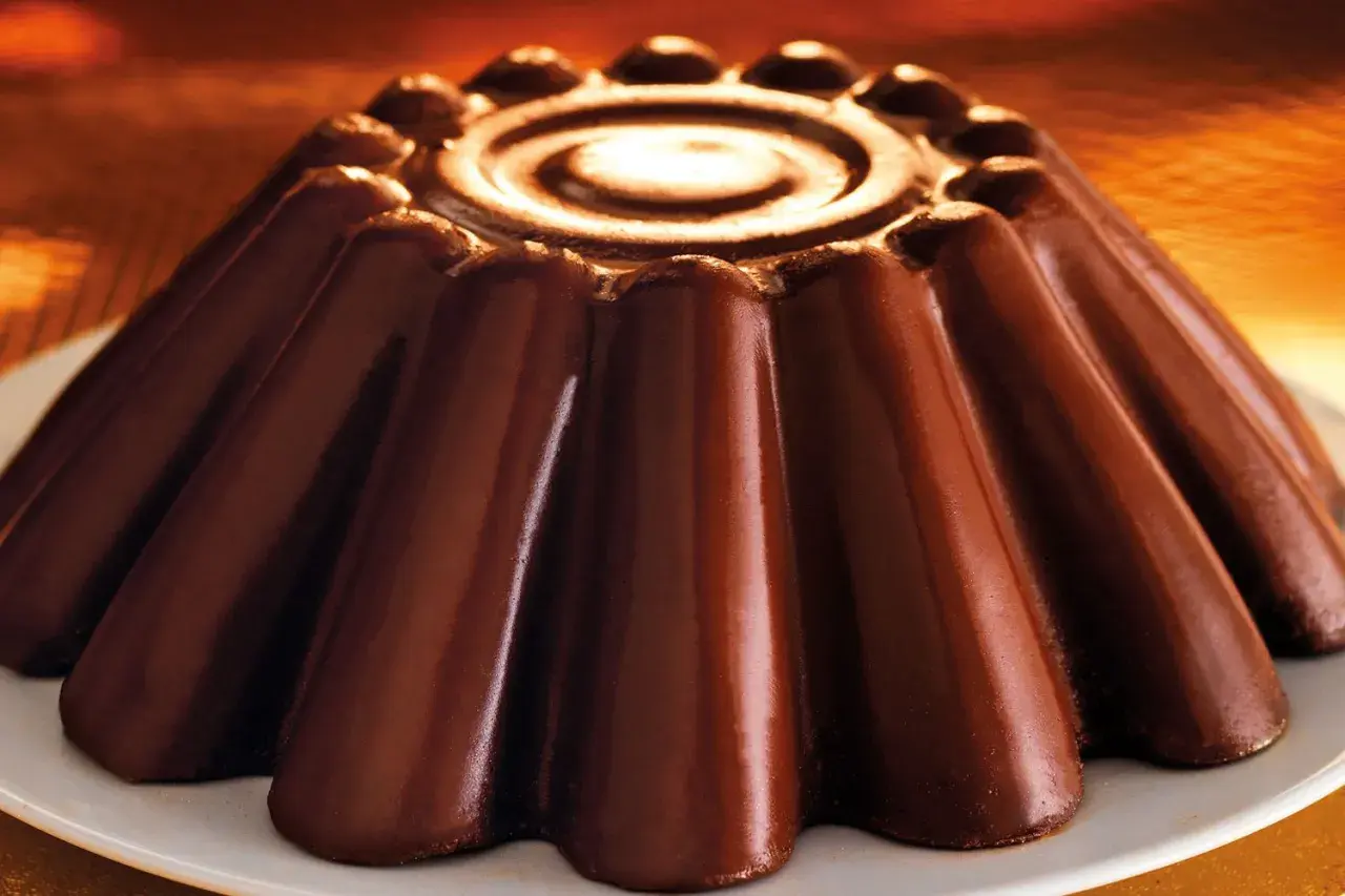 Budino al cioccolato lucido e invitante, con un disegno a spirale al centro e una forma a petali che promette un sapore intenso.