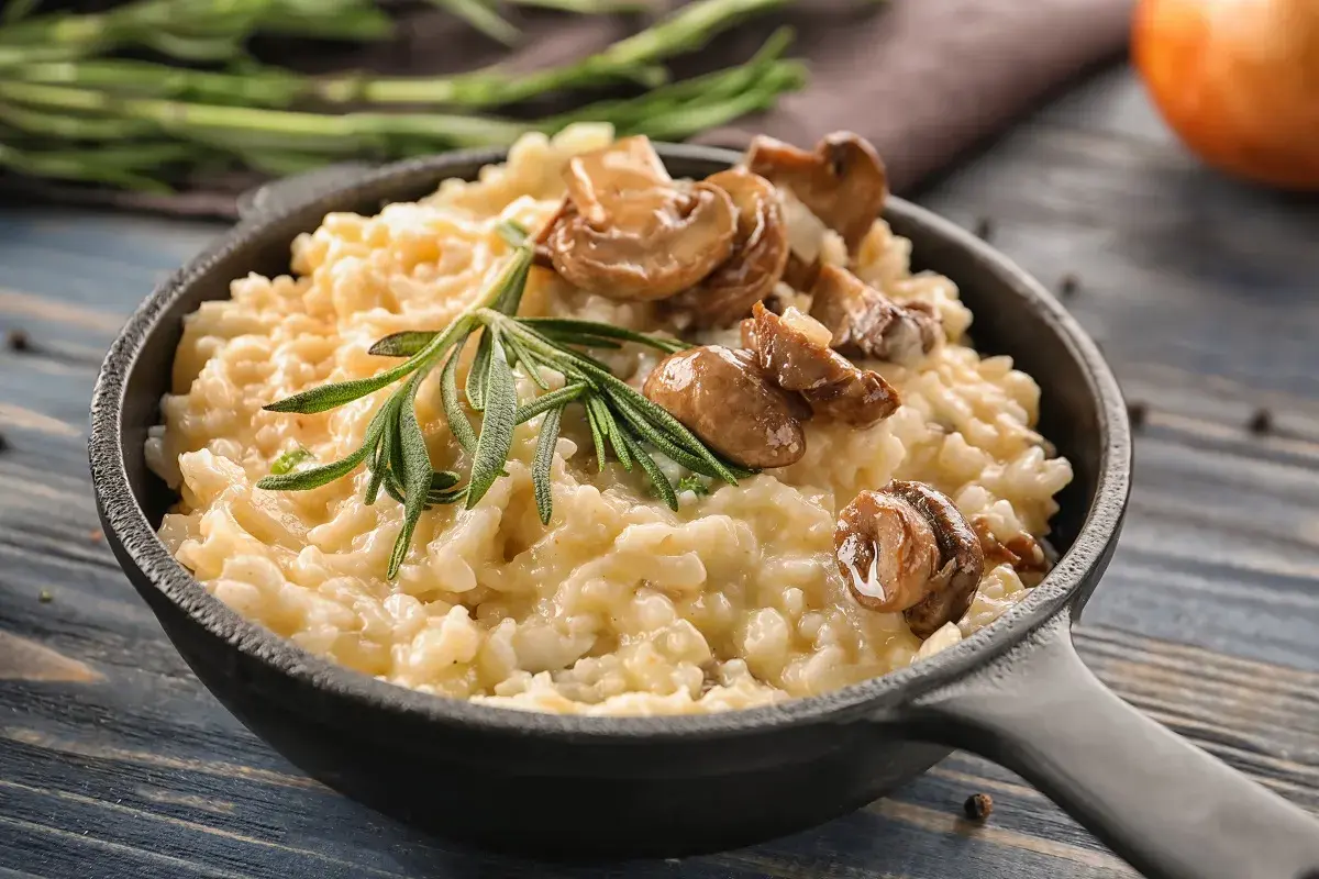 Cremoso arroz italiano con champiñones y romero, servido en sartén de hierro fundido.