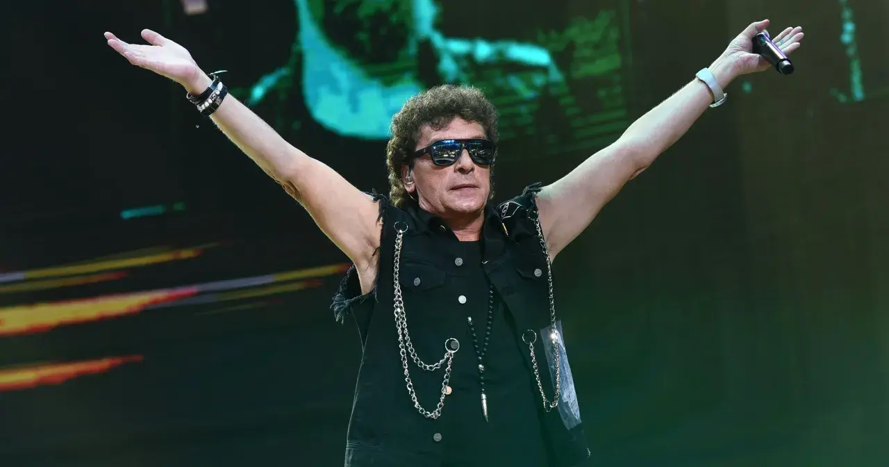 Charyzmatyczny wokalista Lady Pank z podniesionymi rękami, w okularach przeciwsłonecznych, na koncercie.