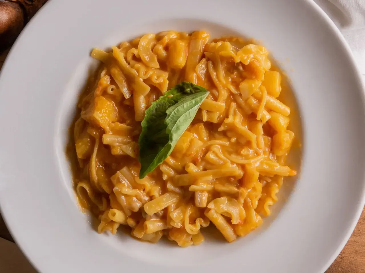 Piatto di pasta patate e provola cremoso, con un tocco di basilico fresco.