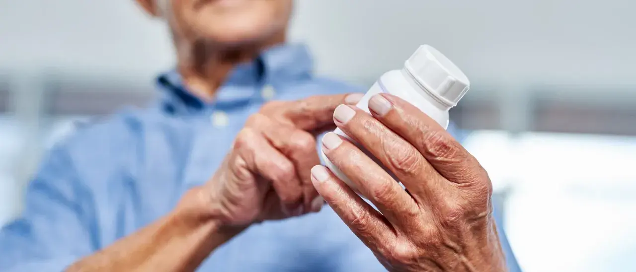 Ältere Hände halten eine Pillendose. Die Glucosamin Wirkung für Gelenke wird hier thematisiert.