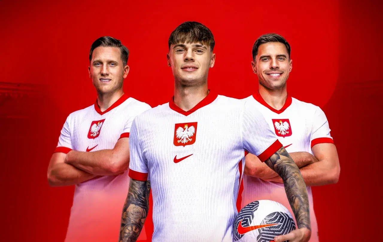 Trzech uśmiechniętych piłkarzy reprezentacji Polski w białych koszulkach z godłem orła. Jeden z nich trzyma piłkę.