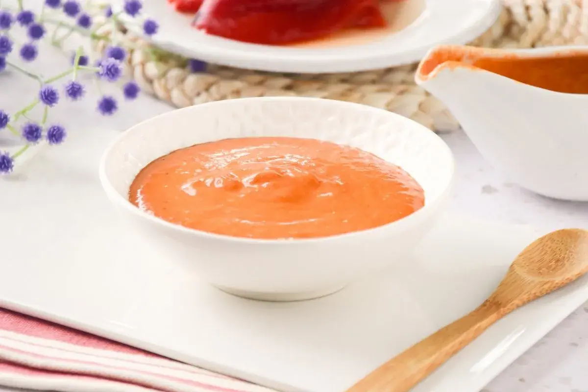 Un cuenco blanco lleno de cremosa salsa de pimientos del piquillo, lista para acompañar tus platos.