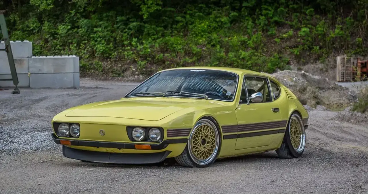 Gul vw sp2 med guldfärgade fälgar står på grusväg.