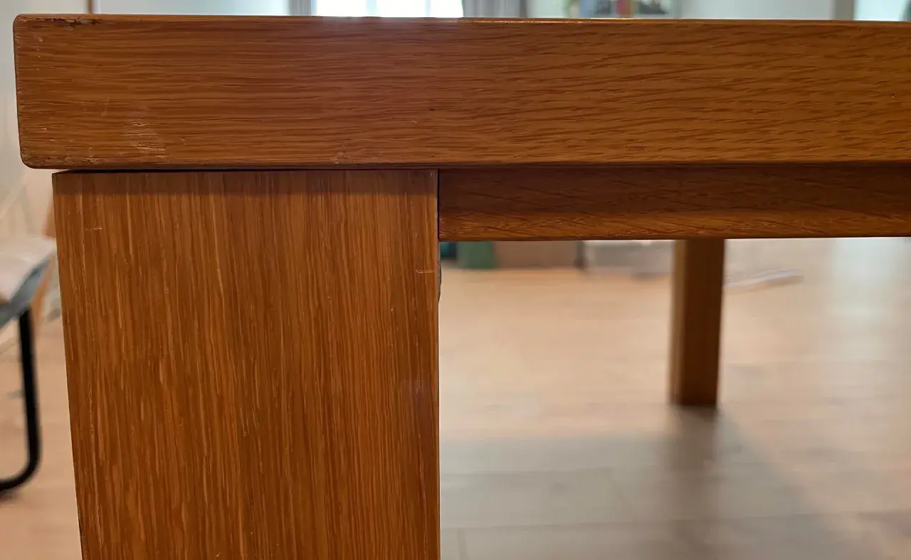 Detaljbild av ett träbord i fanér, redo för renovering.