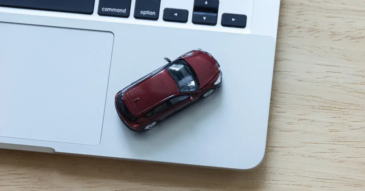 Czerwony samochodzik na laptopie. Zastanawiasz się, ile kosztuje wystawienie samochodu na OLX?