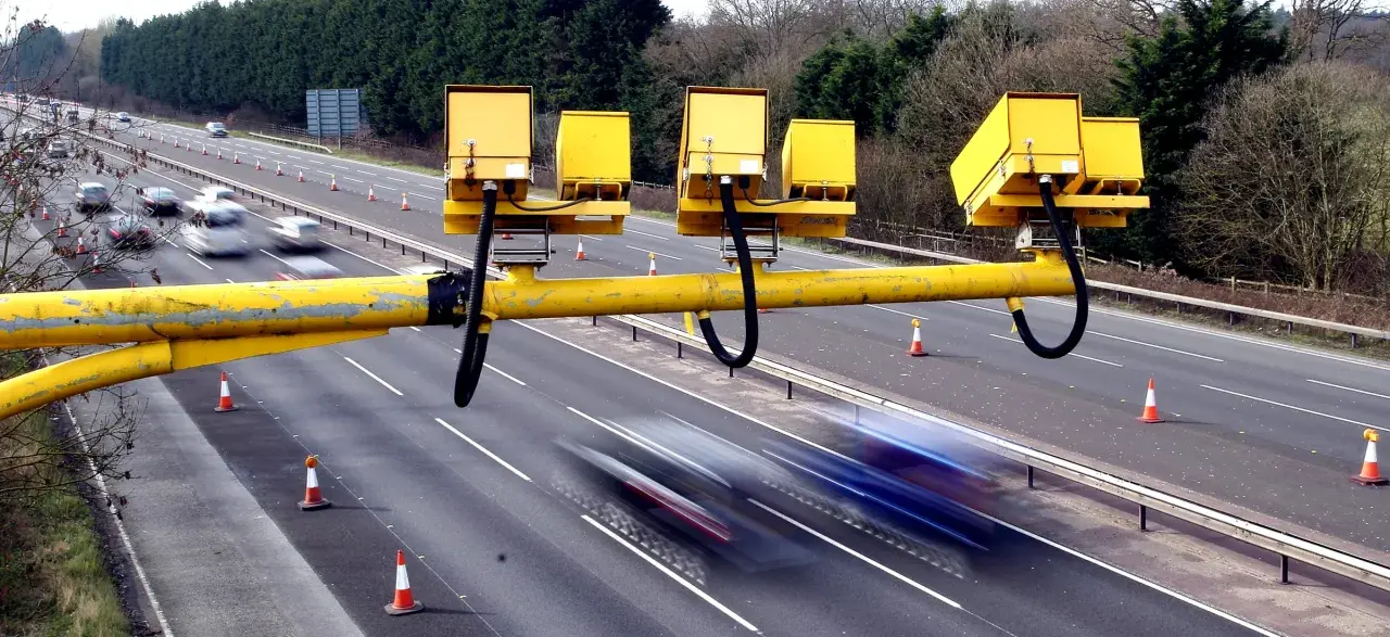 Żółta konstrukcja z kamerami nad drogą, monitorująca odcinkowy pomiar prędkości S8.