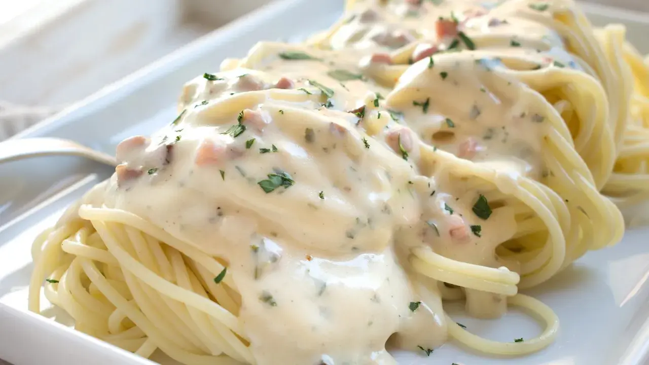 Spaghetti mit cremiger Carbonara-Sauce und Speckstücken, garniert mit Petersilie.