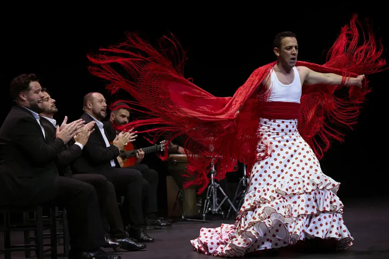 Antonio, cantante flamenco, baila con pasión, su mantón rojo ondea mientras los músicos le acompañan.