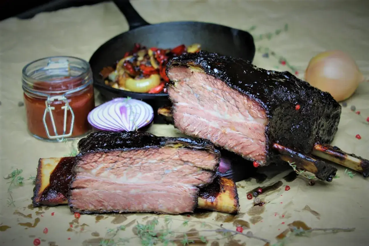 Zart geschmorte short ribs, glasiert und saftig, mit Beilagen wie Zwiebeln und Sauce.