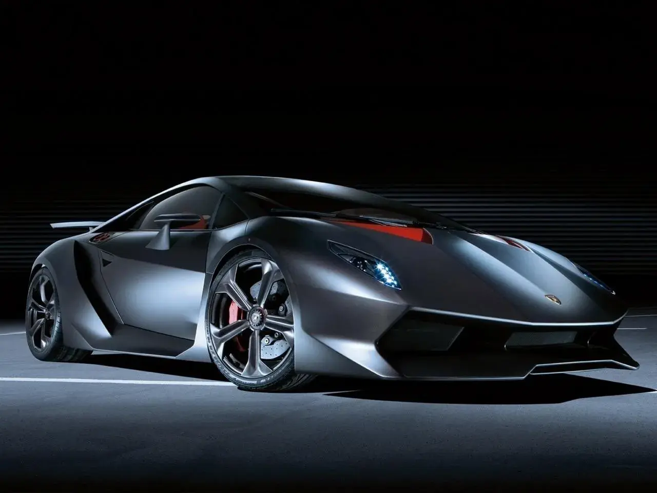Srebrny Lamborghini Sesto Elemento z czerwonymi akcentami na masce, prezentujący swoją agresywną sylwetkę na ciemnym tle.
