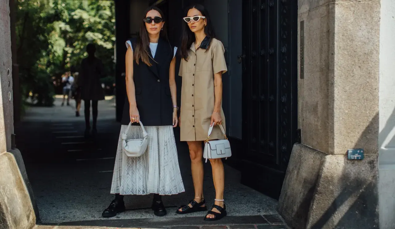Deux femmes stylées montrent comment porter blazer sans manche femme. L'une porte un blazer noir sur une jupe plissée, l'autre une robe chemise beige.