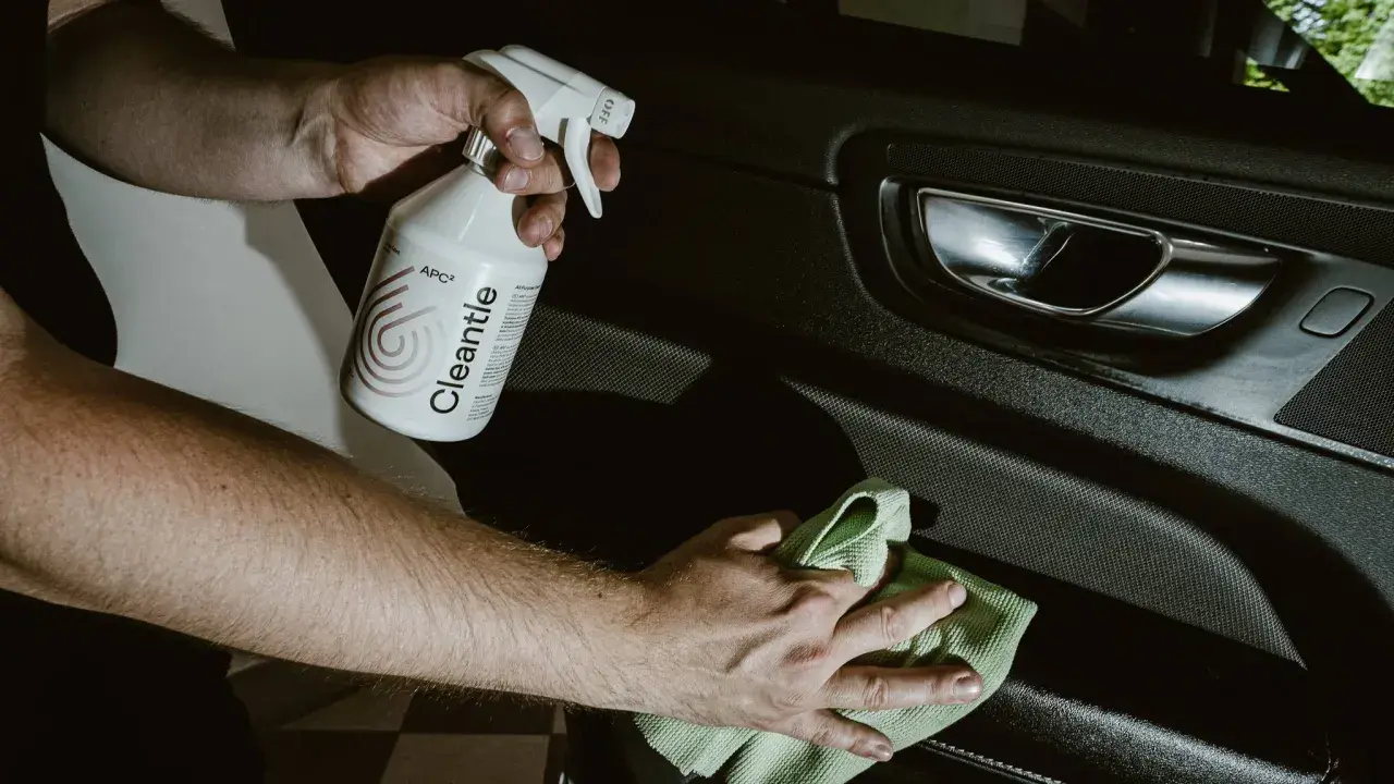 Ręce czyszczą wnętrze samochodu, używając zasadowego APC Cleantle i zielonej mikrofibry.
