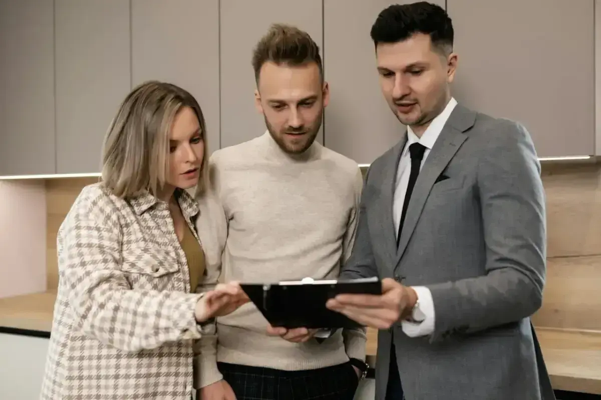 Para młodych ogląda ofertę mieszkania z agentem nieruchomości. Wynajmujący omawia szczegóły umowy.