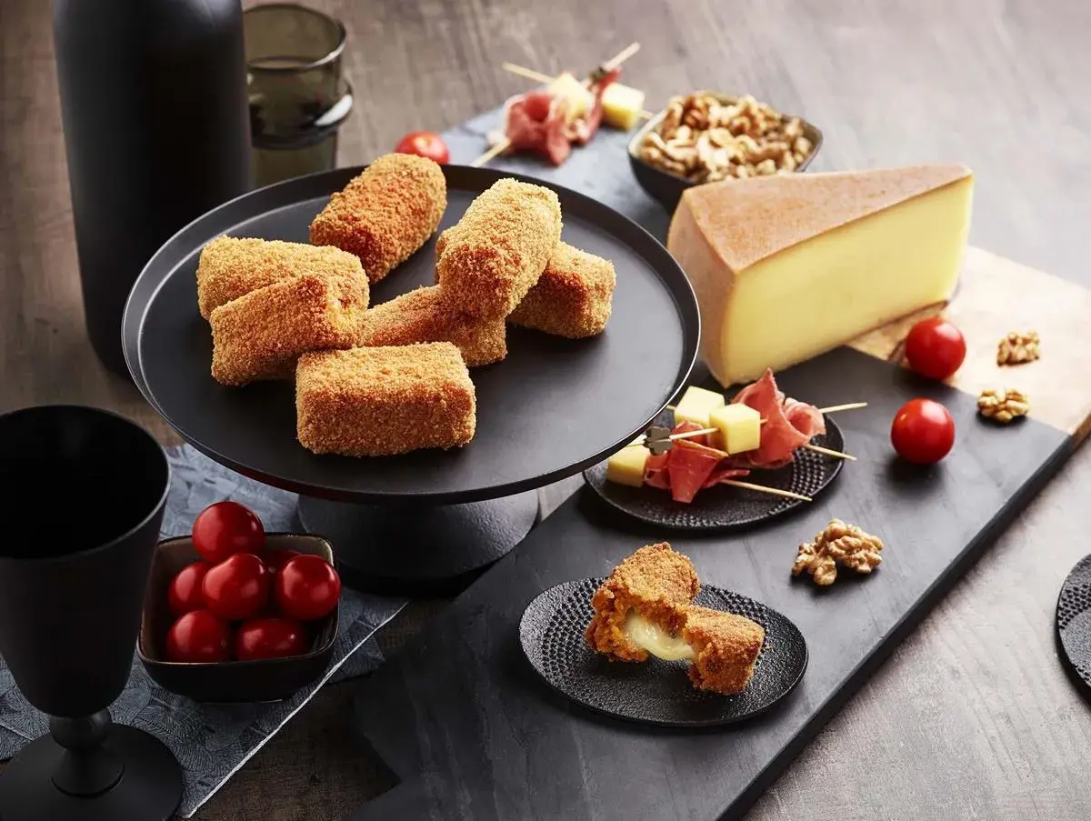 Croquettes dorées, garnies d'un fromage fondant, parfaites pour une raclette gourmande. Tomates cerises et noix accompagnent ce délice.
