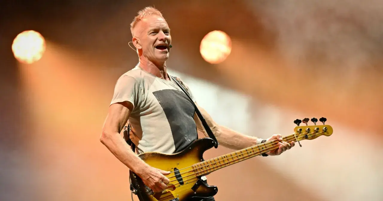 Wokalista The Police, Sting, gra na gitarze basowej podczas koncertu.