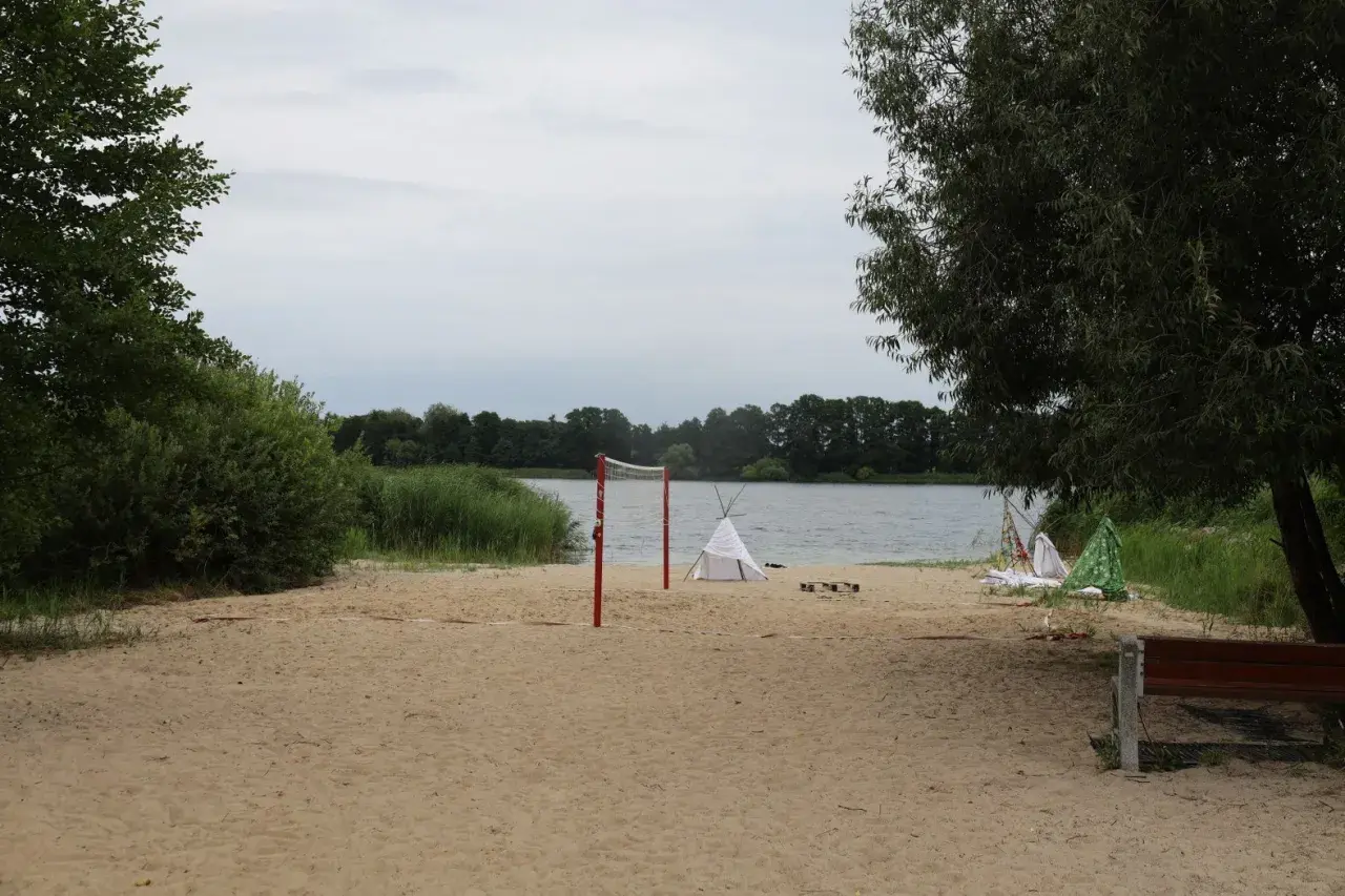 Plaża nad jeziorem Lednica z siatką do siatkówki i namiotami tipi.