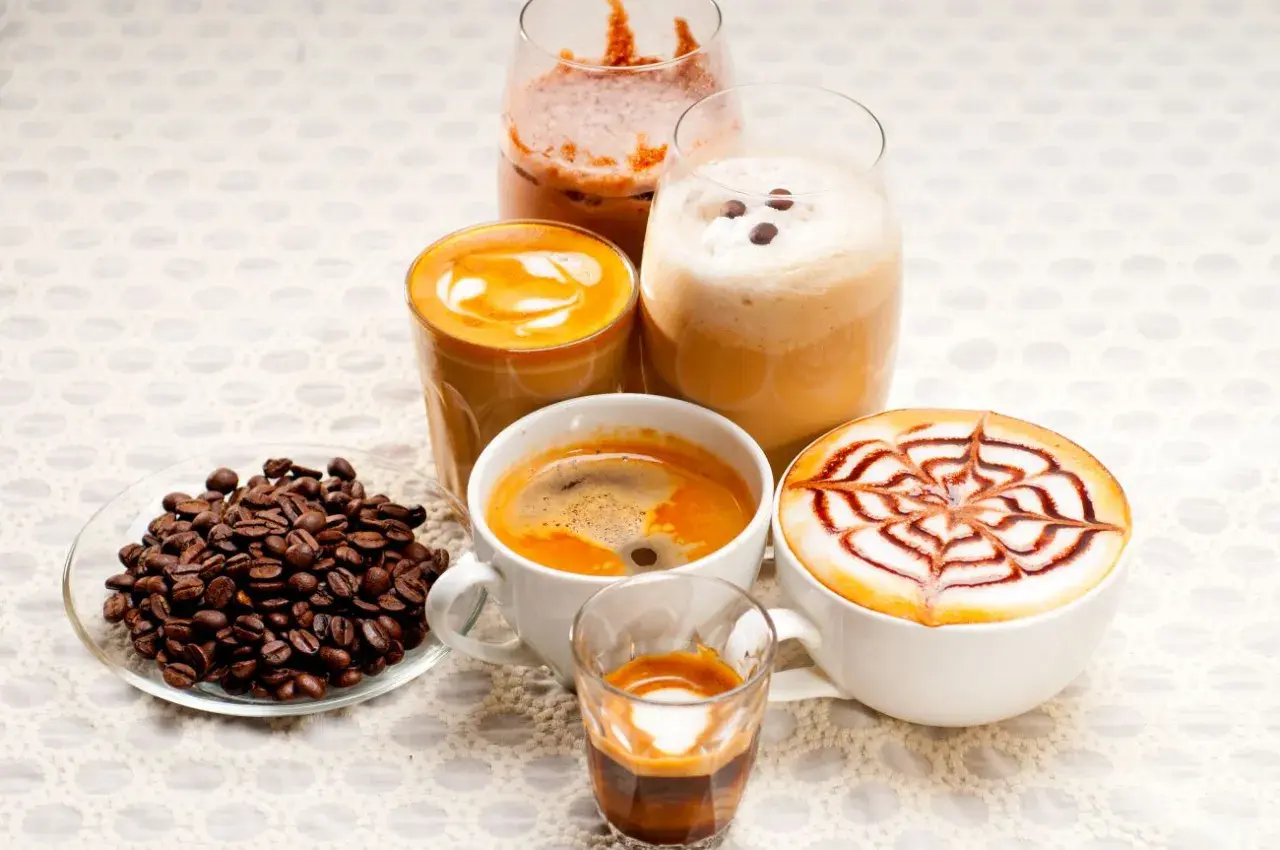 Różnorodne kawy, w tym latte z wzorem, espresso i napoje mrożone, idealne na keto dietę. Obok ziarna kawy.