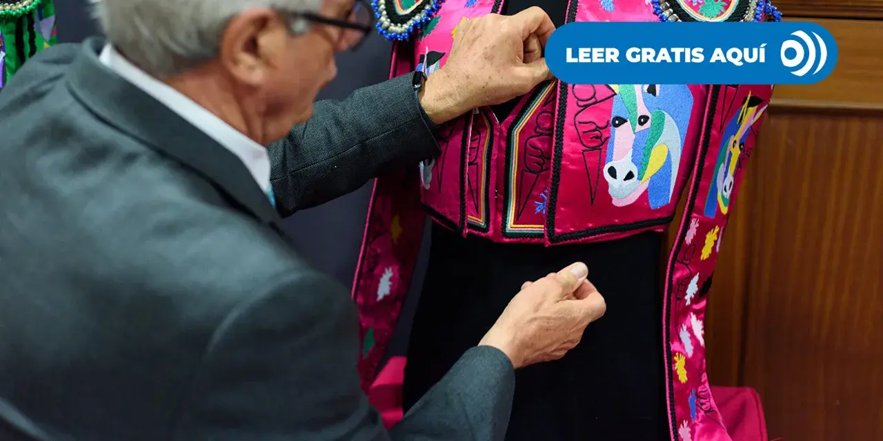 Un hombre ajusta un traje de luces rosa con caballos bordados, listo para una corrida en Madrid.