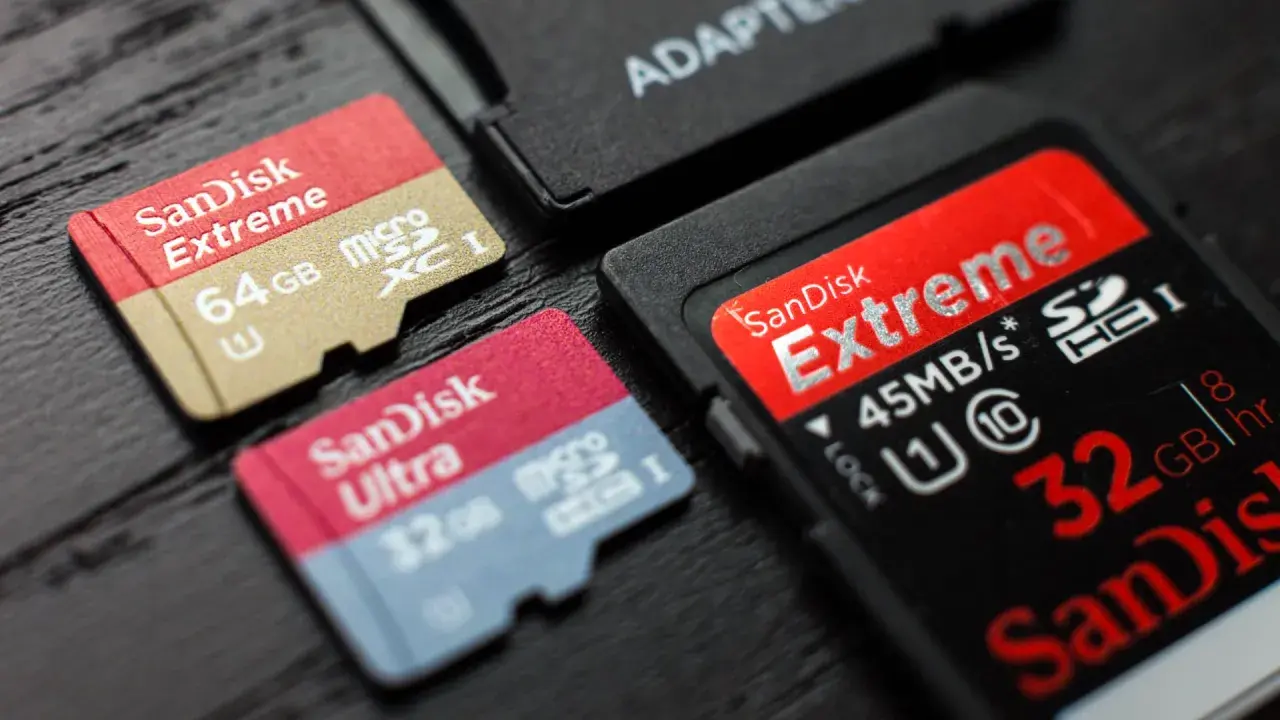 Karty pamięci SanDisk Extreme i Ultra, w tym 64GB microSDXC i 32GB microSDHC, obok adaptera. Różnice między SDXC a SDHC są widoczne.