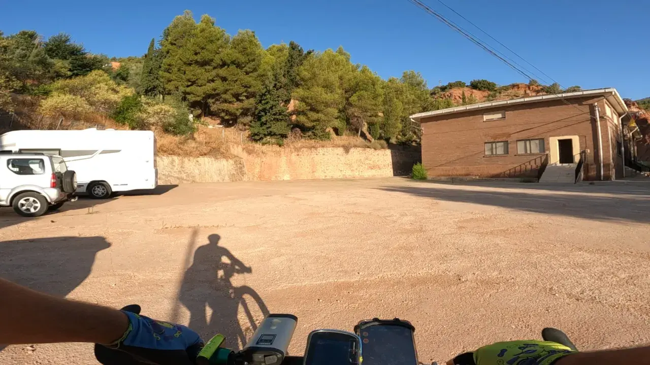 Encuentra la bogarra en este camino de tierra, con una caravana y un edificio de ladrillo al fondo.