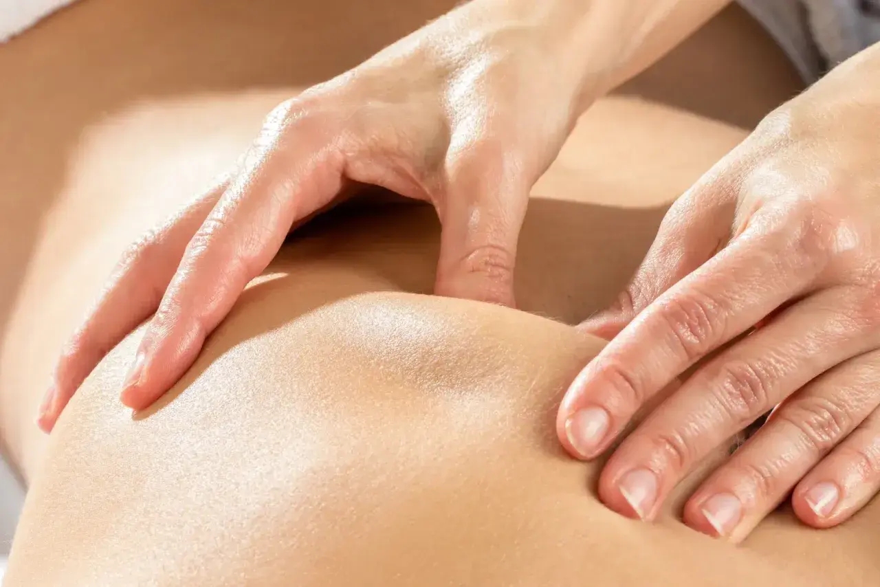 Mains expertes prodiguant un massage kinésithérapique apaisant, soulageant les tensions musculaires.