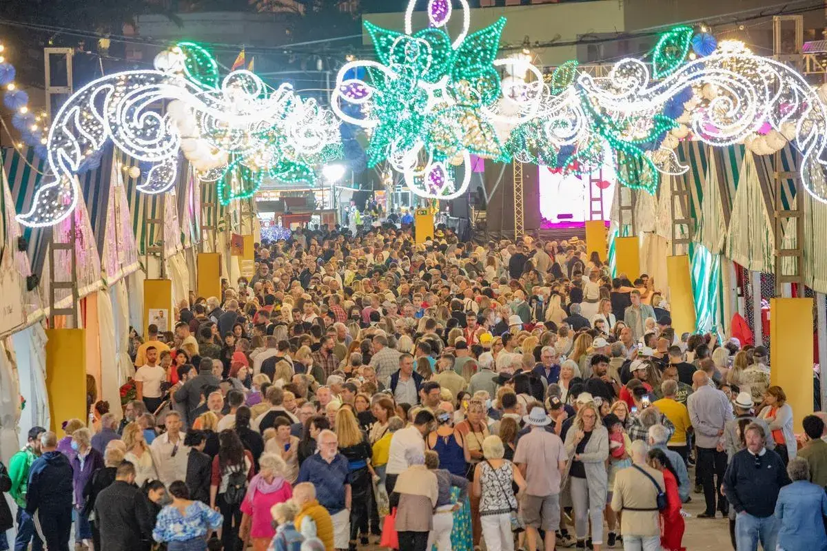 Multitudinaria feria nocturna con arcos de luces y puestos.