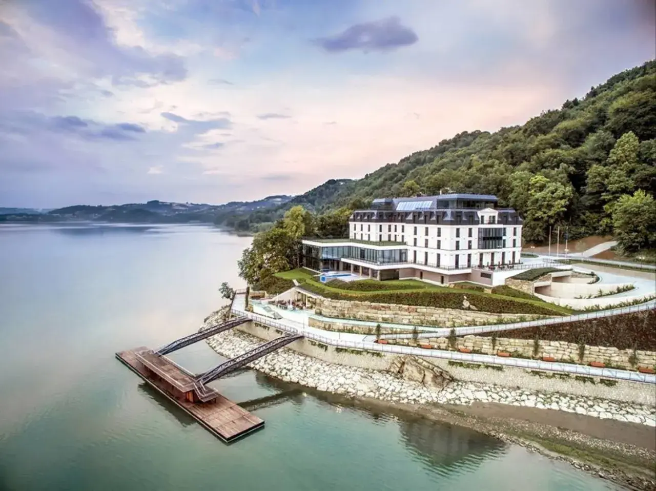Nowoczesny hotel nad jeziorem, idealny na romantyczne miejsca w Polsce. Widok na wodę, las i pomost.