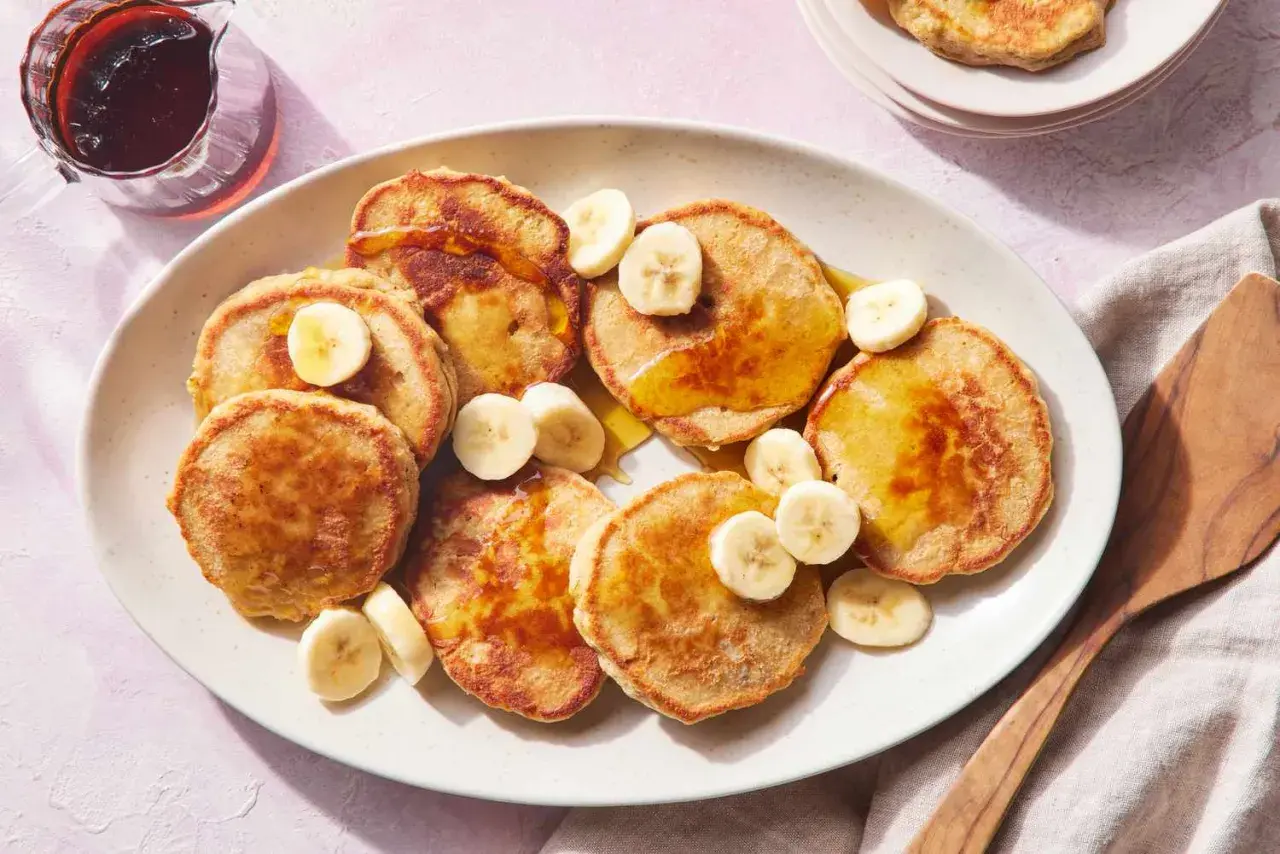 Tortitas de avena y plátano doradas, cubiertas con rodajas de plátano y sirope. Un desayuno delicioso y saludable.