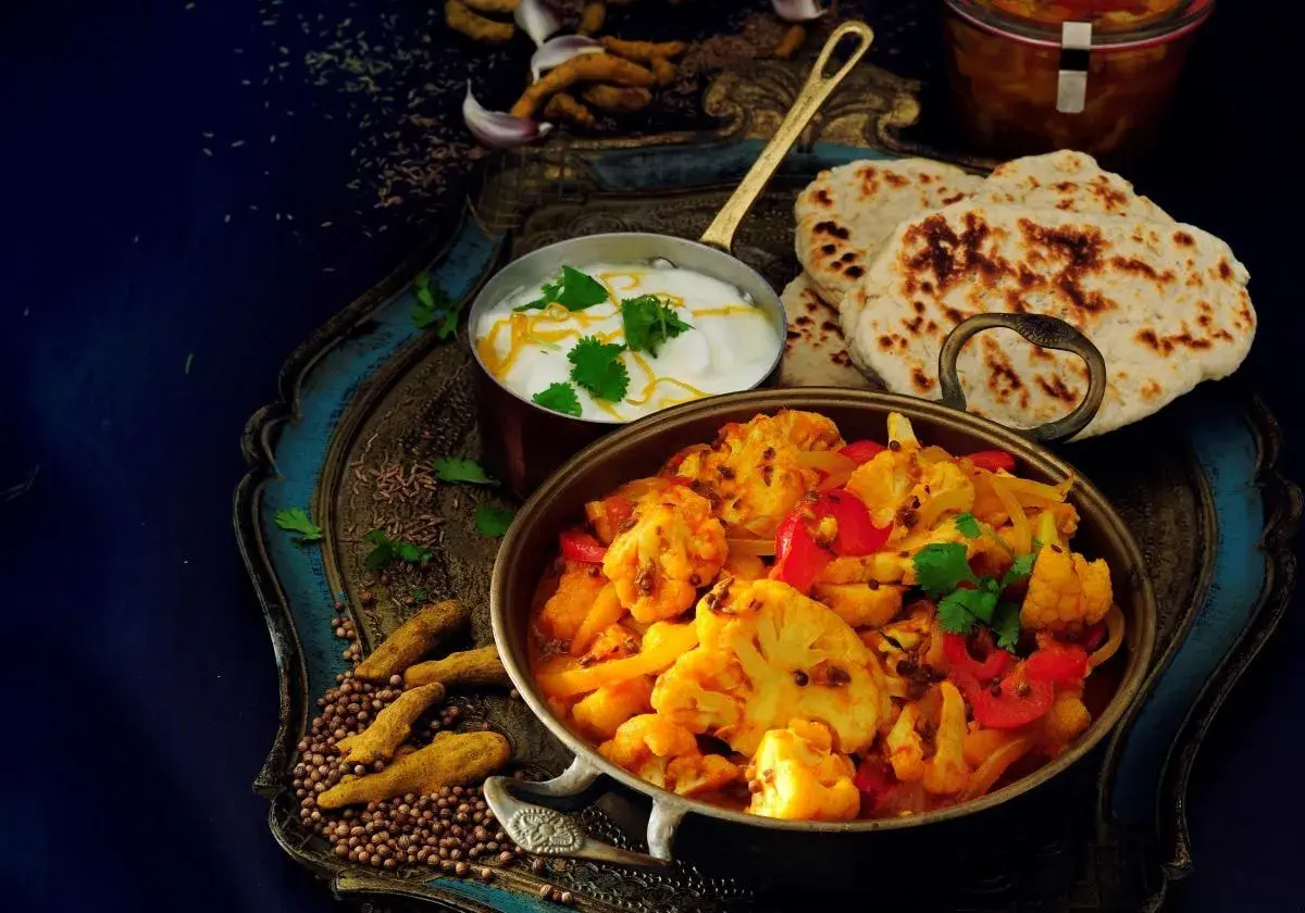 Aksamitne curry z kalafiora z mleczkiem kokosowym, podane z chlebkami naan i jogurtem.