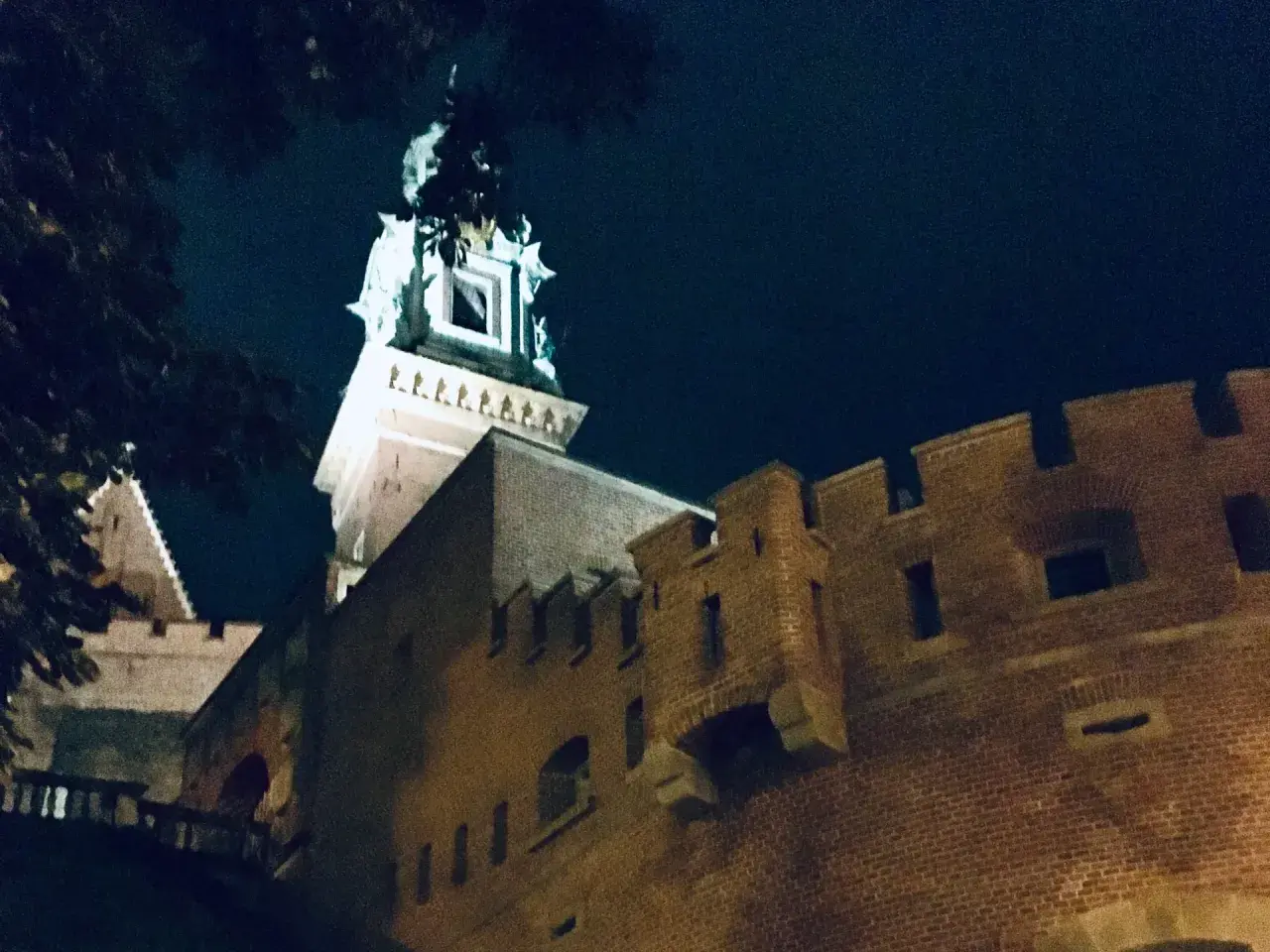 Wieczorne ciekawostki o Krakowie: Wawel nocą, z murami i wieżą oświetloną blaskiem księżyca.