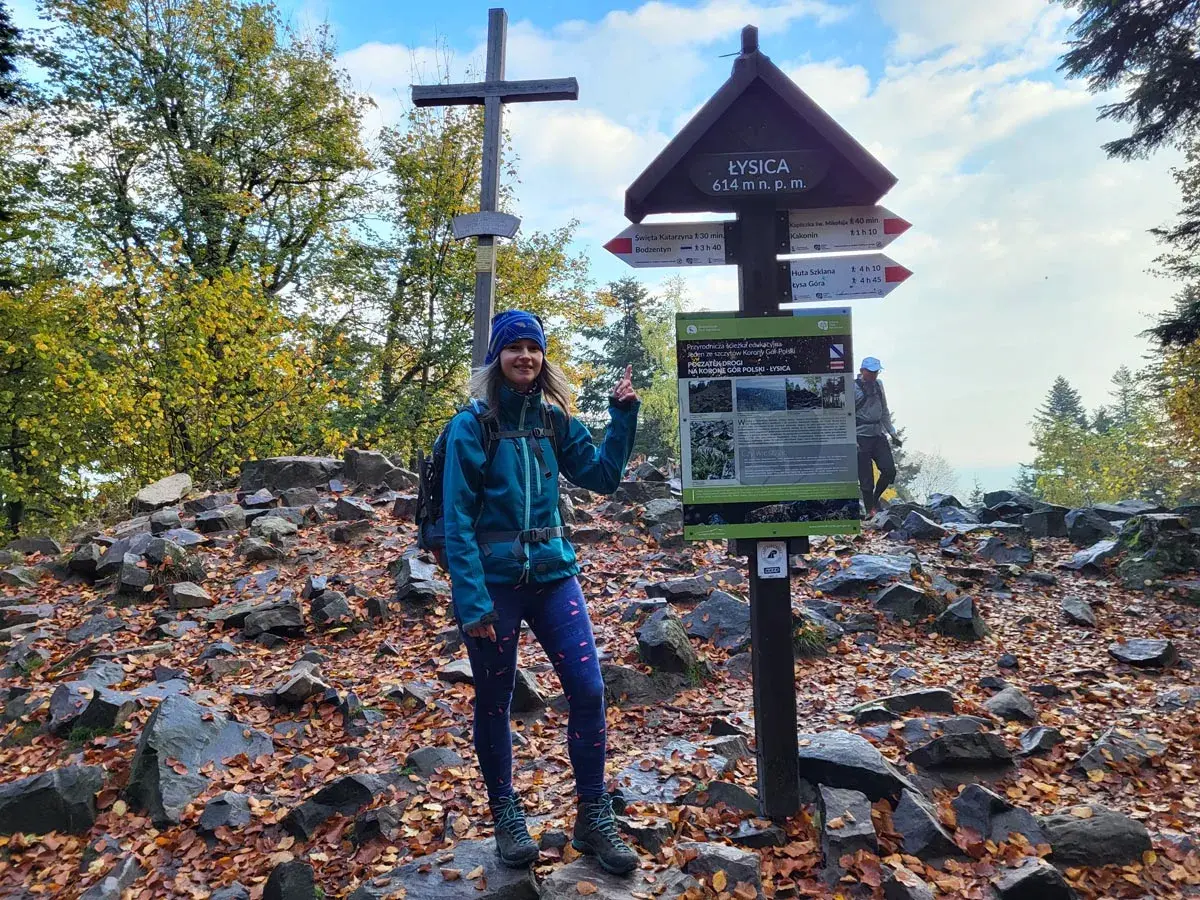 Kobieta na szczycie Łysica, 614 m n.p.m., przy drogowskazie. Jesienny szlak, liście i kamienie.