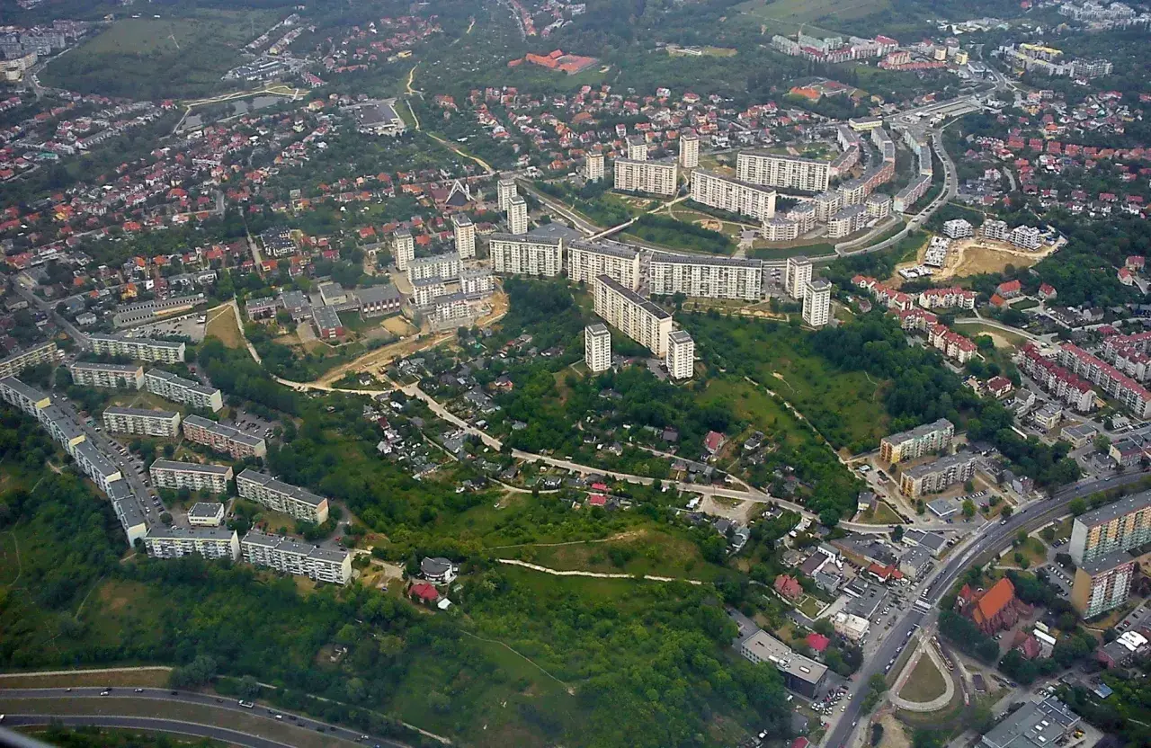 Widok z lotu ptaka na osiedle mieszkaniowe w Gdańsku Suchanino. Długie bloki mieszkalne otoczone zielenią i drzewami.