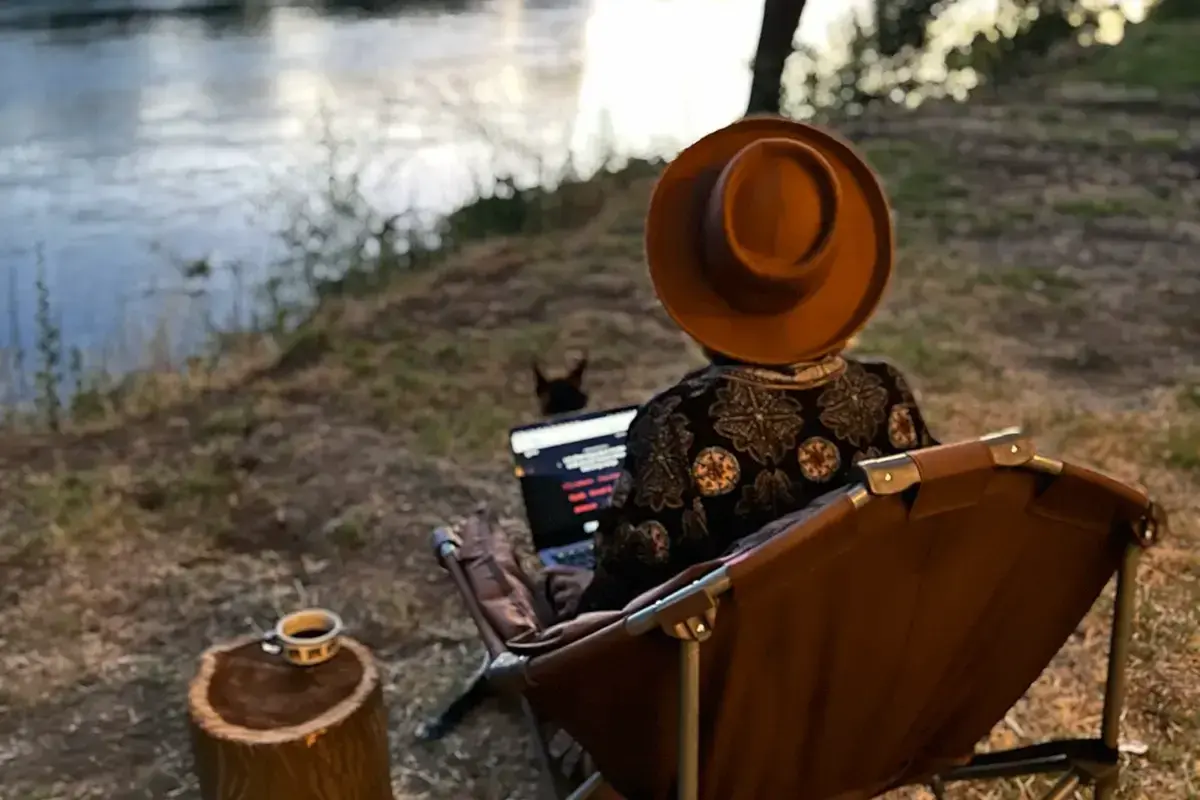 Praca zdalna nad rzeką. Kawa na pniu, piesek i laptop. Tak wygląda życie digital nomad co to znaczy?