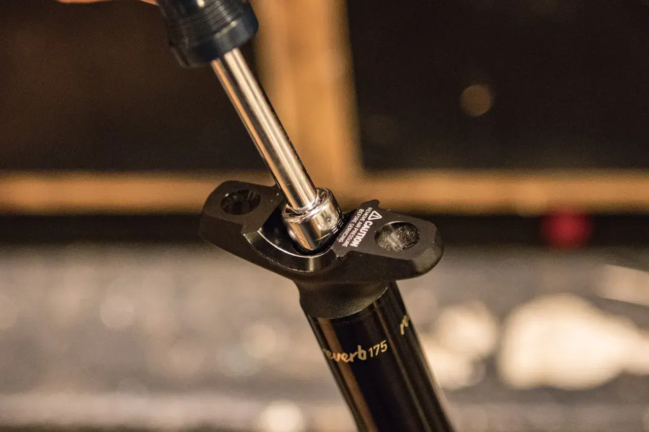 A socket wrench tightens a bolt on a Reverb Stealth dropper post.