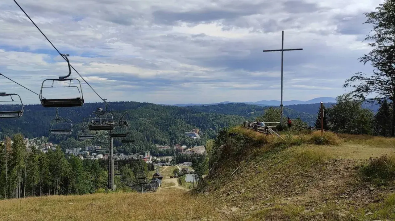 Widok z góry krzyżowej na dolinę z wyciągiem krzesełkowym i zabudowaniami.