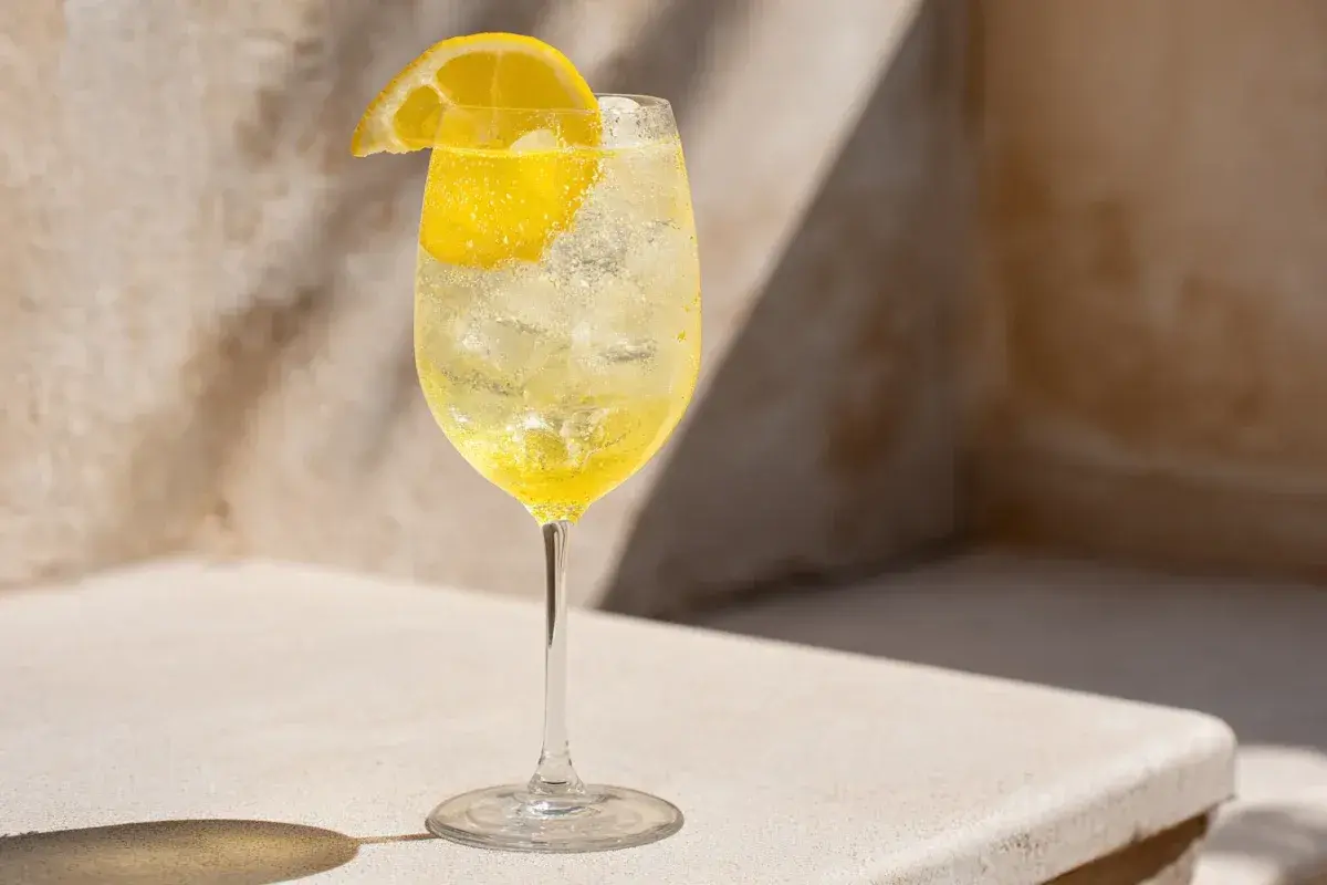 Ett glas med is och en citronskiva, fyllt med en bubblig limoncello sour.