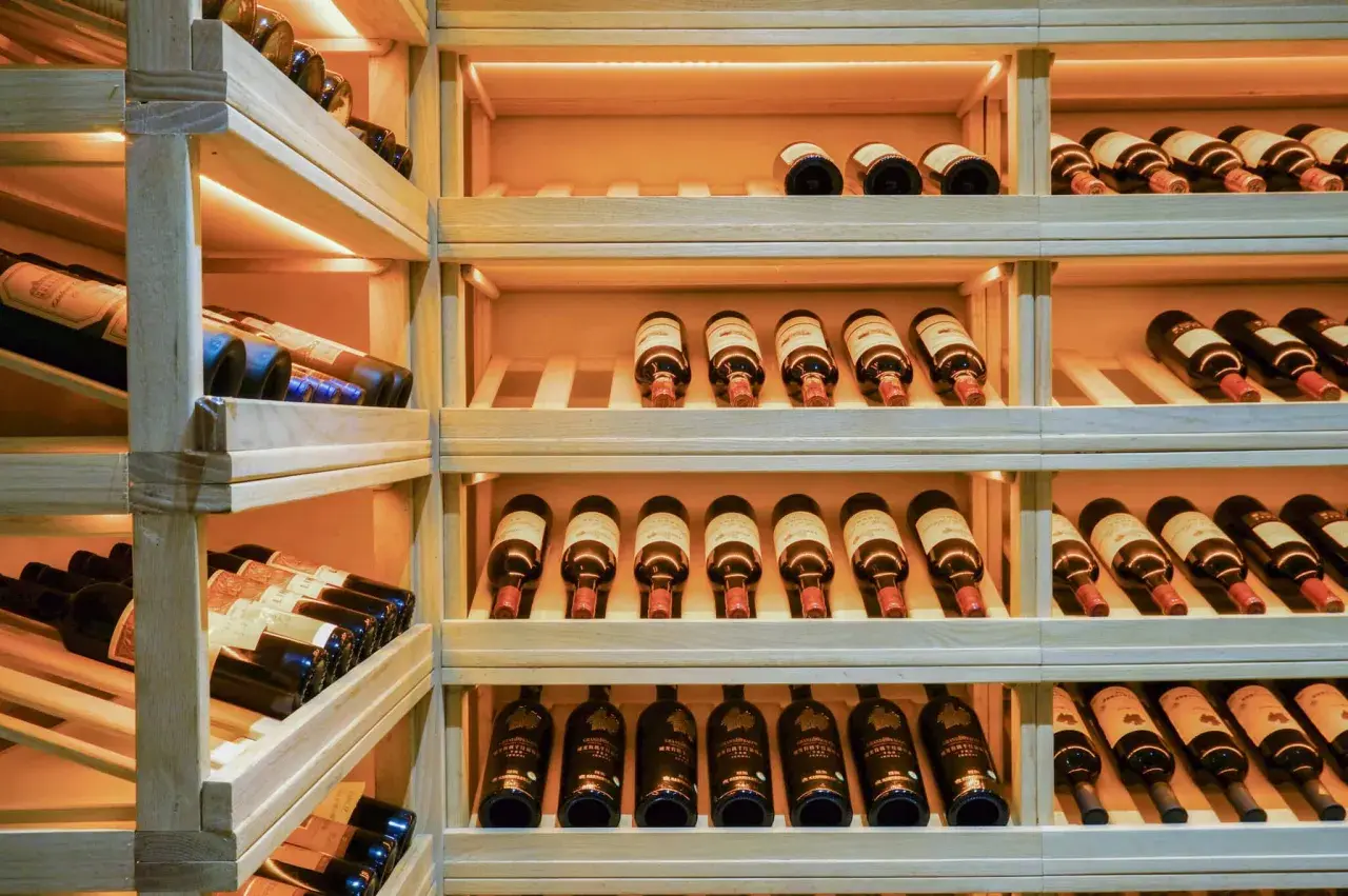 Une cave à vin en bois avec de nombreuses bouteilles. Un guide millésime vin idéal pour choisir la meilleure cuvée.