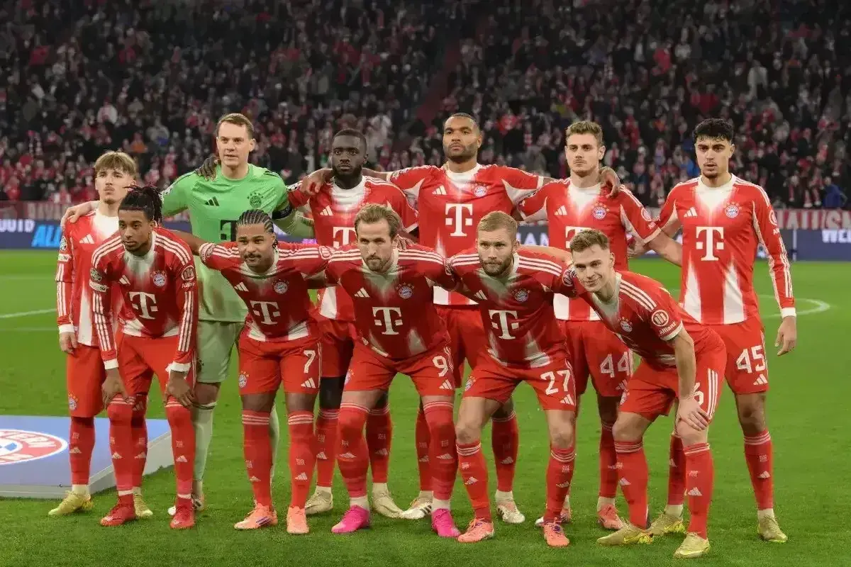 Drużyna piłkarska w czerwonych strojach z białymi pasami, gotowa do gry w Bundeslidze niemieckiej.