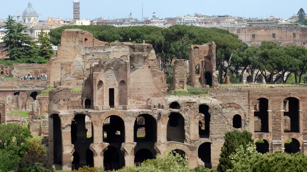 Antiche rovine del **Monte Palatino a Roma**, con archi imponenti e mura di mattoni che si stagliano contro il cielo azzurro.