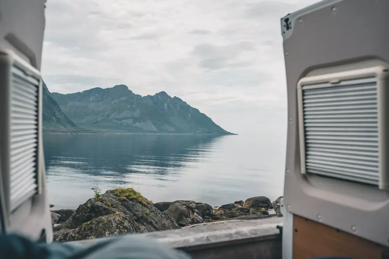 Widok z kampera na spokojne morze i góry w Norwegii. Idealne miejsce na podróż kamperem.