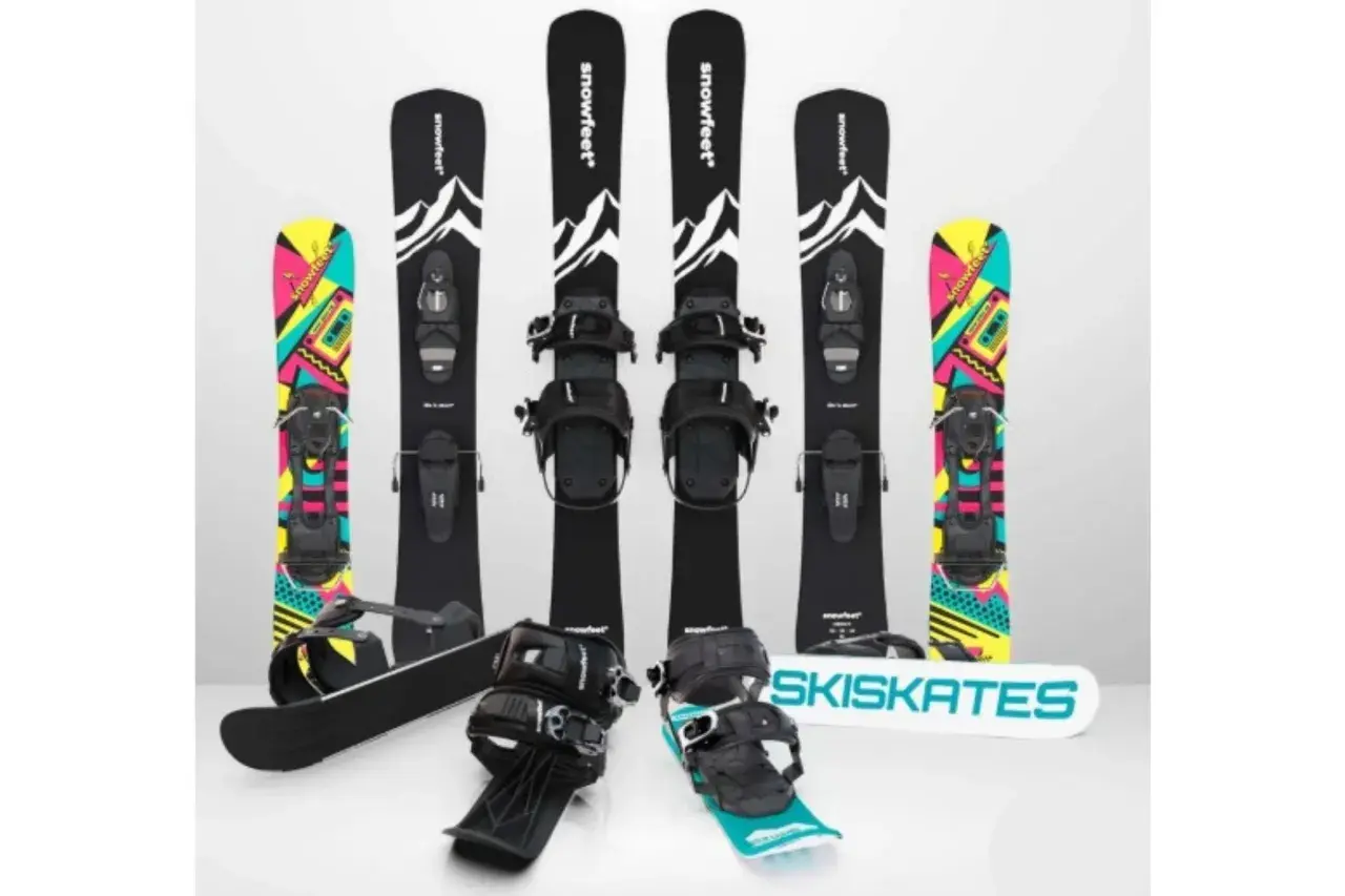 Narty do skakania i snowboardy z kolorowymi grafikami. Dwa zestawy nart do skakania z czarnymi wiązaniami i grafiką górską. Dwa snowboardy z kolorowymi wzorami.