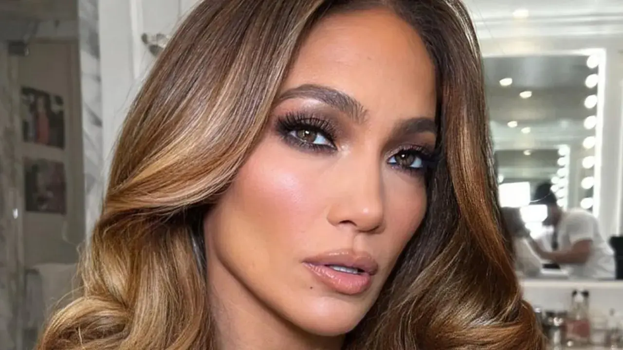 Primer plano de una mujer con maquillaje glamuroso y unos preciosos reflejos en pelo castaño que brillan con la luz.
